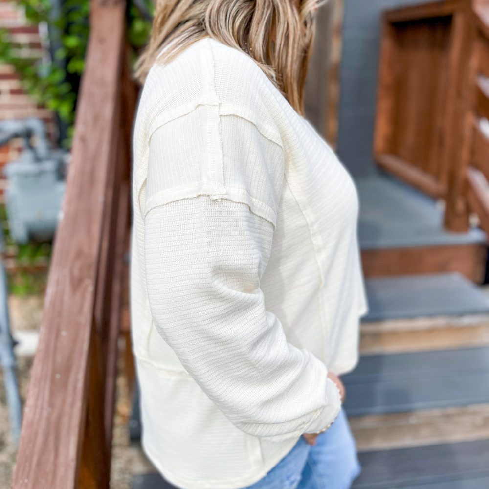 Lovely Chili Cream Patchwork Top, cream long sleeve top with a light ribbed texture, v-neck, front pocket, outside seem edge details. 