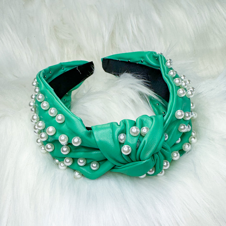 green, faux leather headband covered in white pearls, knot middle detail. 