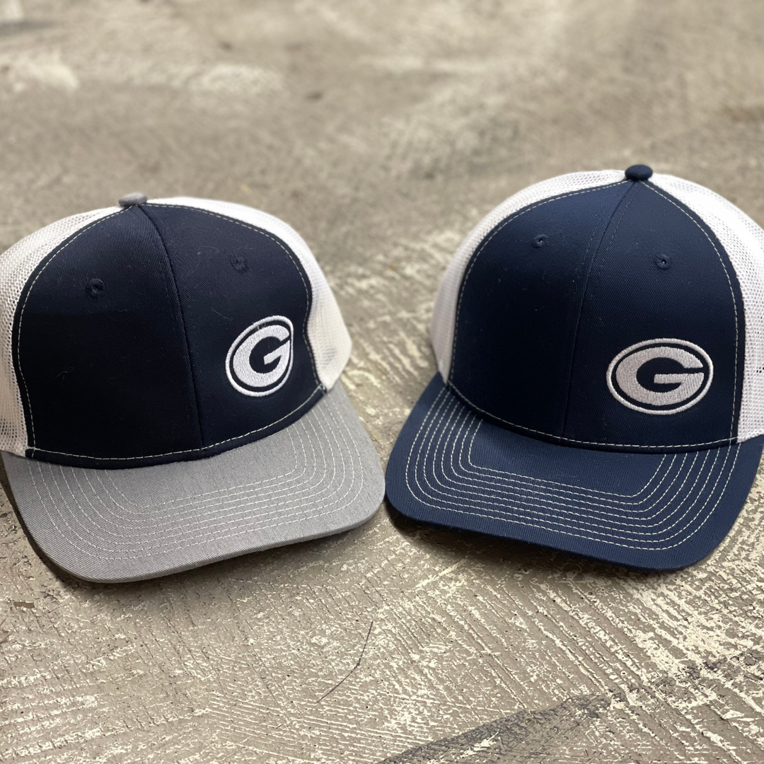 greenwood bulldog embroidered snapback hat. One hat has a navy front panel, white flesh, grey bill with a white embroidered greenwood g. The other has a navy front with navy bill, white mesh, with a white embroidered g on the front. 
