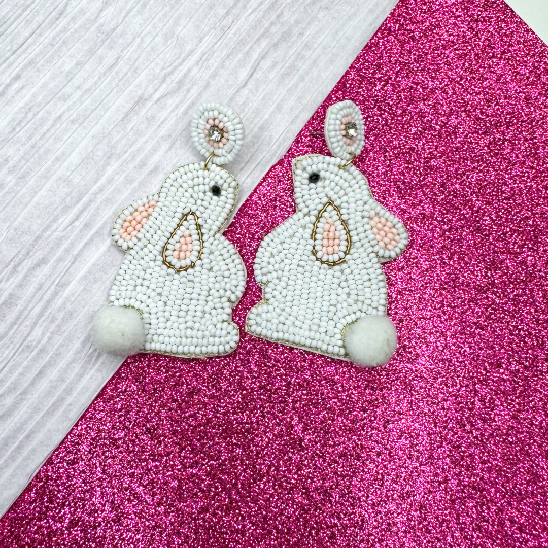 easter beaded earrings, white bunny made out of white beads, with pink bead accents, black bead eye, clear rhinestone, white pom pom tail, post style earrings with felt backing. 