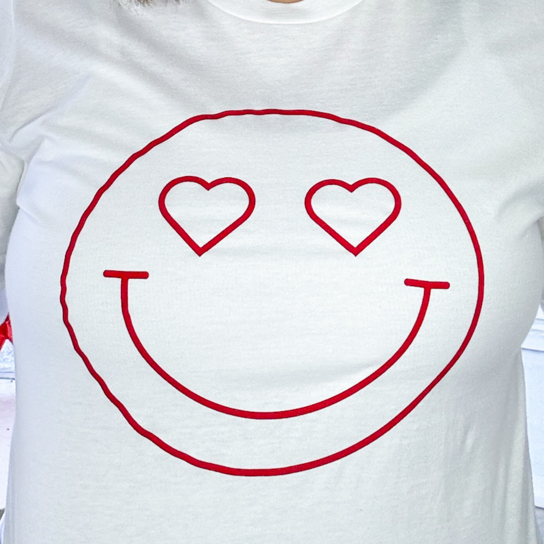 white long sleeve graphic valentine's day shirt with a dark red heart eyes smiley face that is velvet