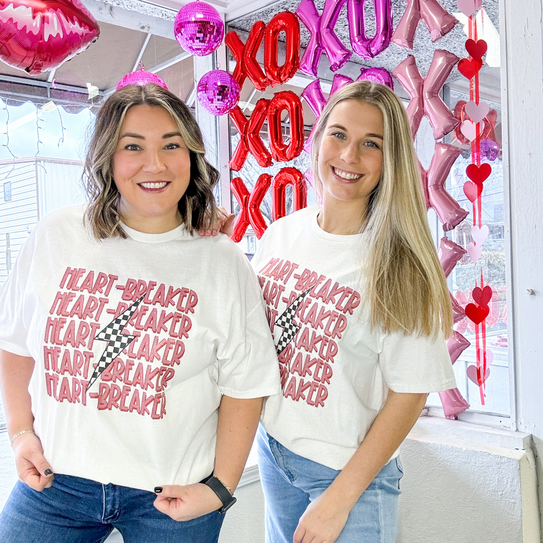 valentine's graphic white t-shirt, heart breaker listed five times in a redish, pink lettering with a checked lightning bolt down the middle