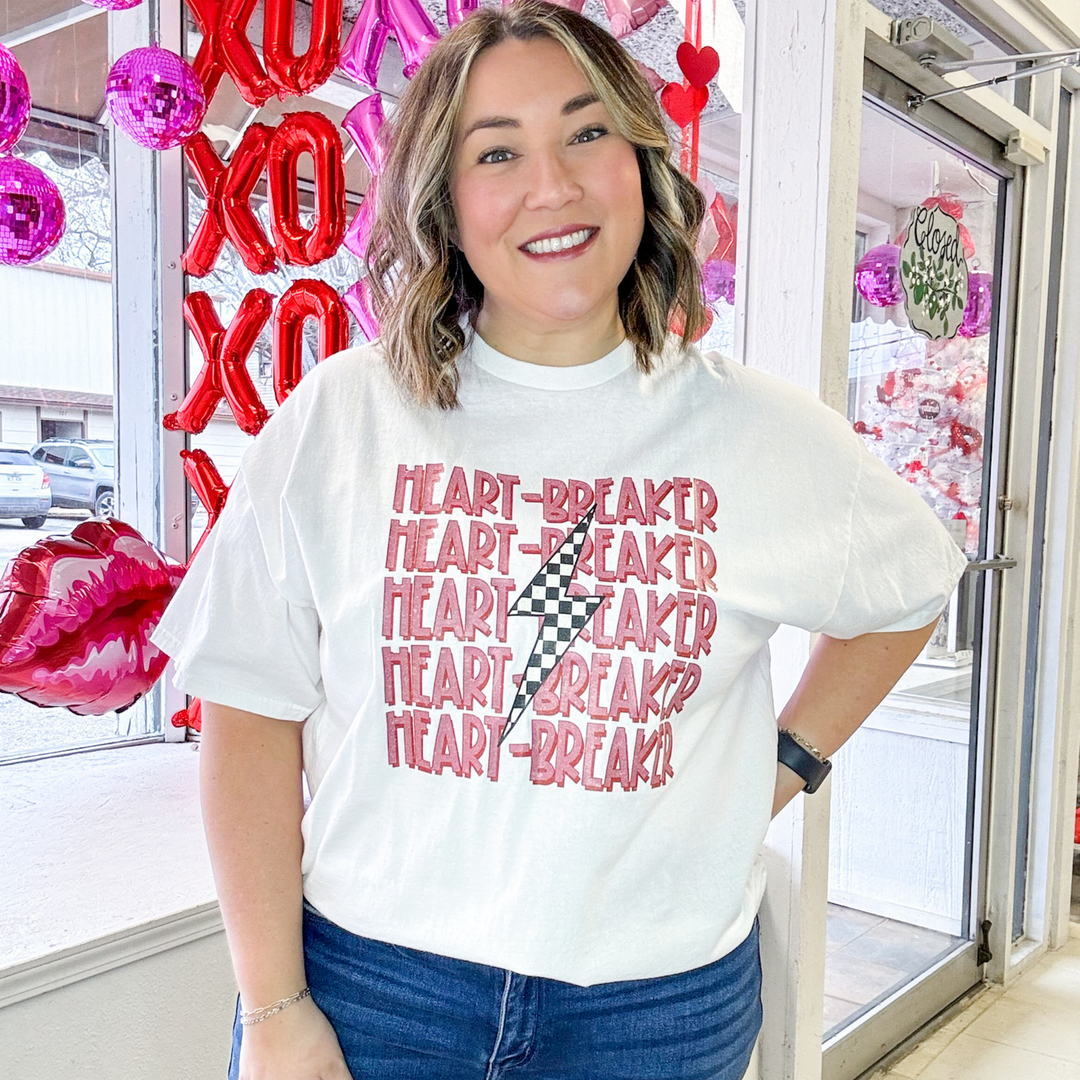 valentine's graphic white t-shirt, heart breaker listed five times in a redish, pink lettering with a checked lightning bolt down the middle