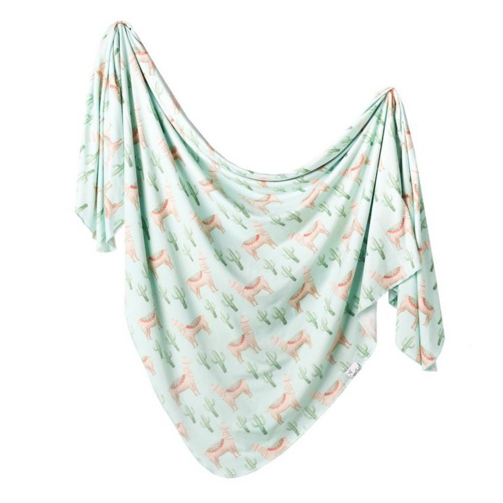 copper pearl cusco swaddle blanket. green background with decorated llamas and cactuses. 