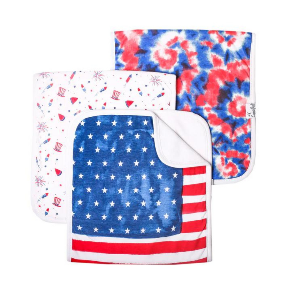 copper pearl patriotic 3 pack of burp cloths. one with american flag print. one with a white background with fireworks, watermelons, patriotic top hat. one with red white and blue tie dye. 
