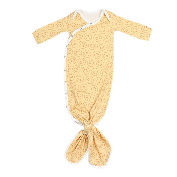 copper pearl knotted baby gown, vance print, yellow background with dark yellow smiley faces, white trim, snap button, knotted at the bottom so it can grow with baby. 