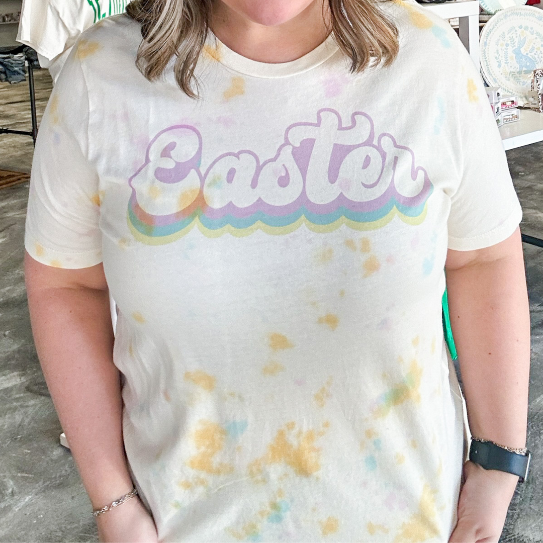easter tee, watercolor tie dye tee shirt, easter in a bubble cursive font in lavender, blue and yellow. 