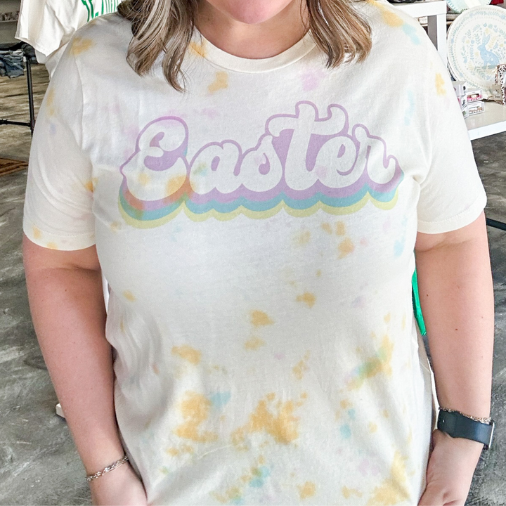 easter tee, watercolor tie dye tee shirt, easter in a bubble cursive font in lavender, blue and yellow. 