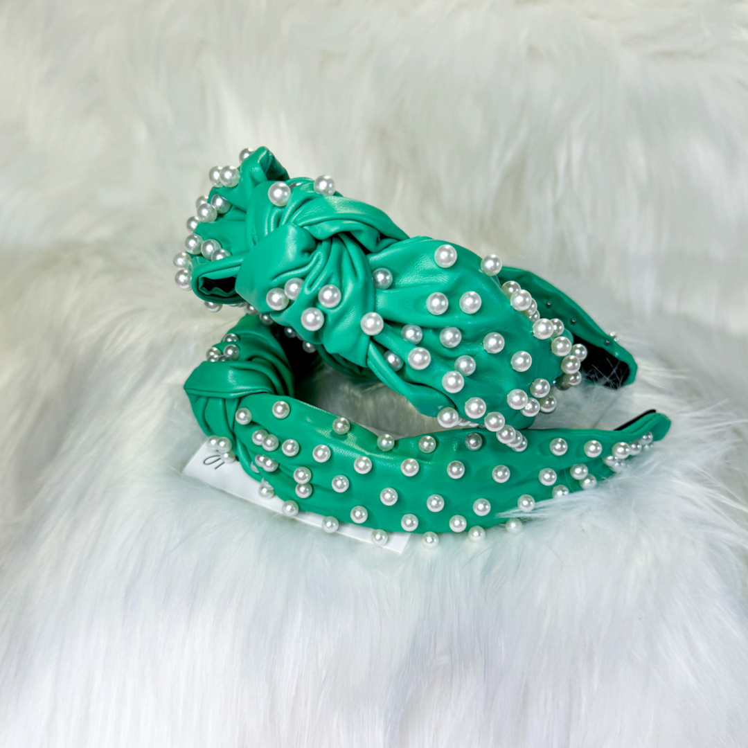 green, faux leather headband covered in white pearls, knot middle detail. 