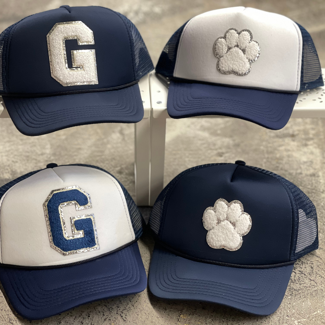 Greenwood foam hat with chenille patch. One is full navy with white G with silver trim. One is full navy with white paw print with silver trim. One is white and navy with navy G with silver trim. One is white an navy with navy paw print silver trim.