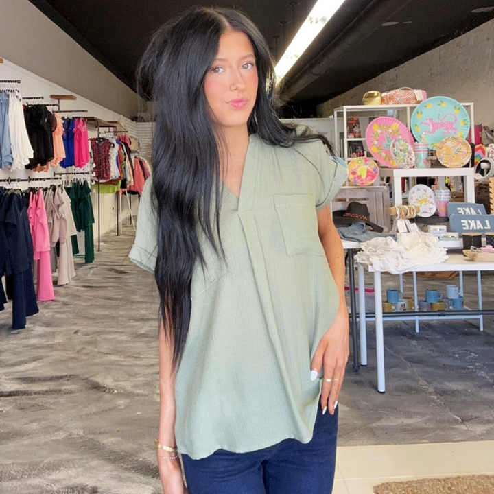 Easy To Style light olive Woven Top, woven women's short sleeve top with v-neck with detail. double front pocket detail. back button detail going down the center.