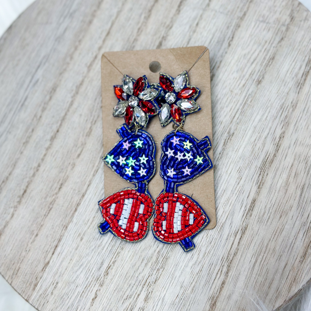 patriotic heart aviator beaded earrings, the lenses are in the shape of hearts, one heart is red and white stripes, one heart is blue with white stars, post is red and white gems.