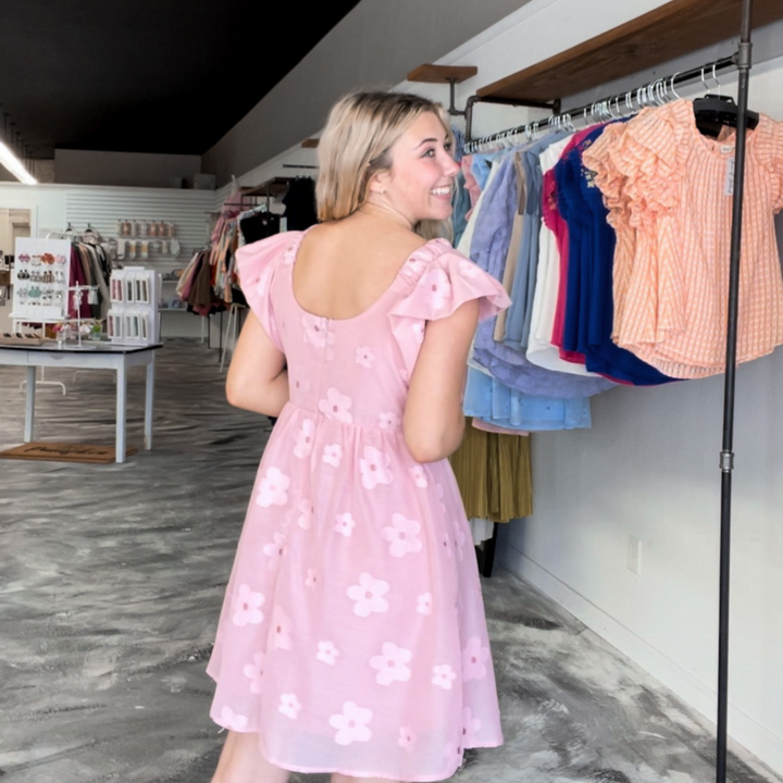 light pink flowy mini dress, embroidered light pink flowers with ruffle sleeves.