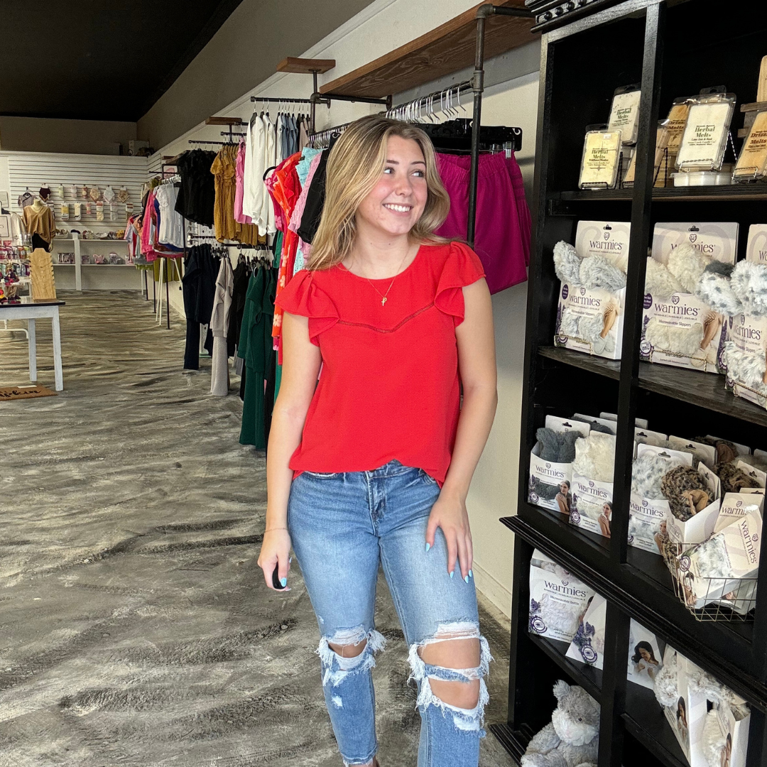 Red blouse with ruffle cap sleeves and a single v-shape across the chest.