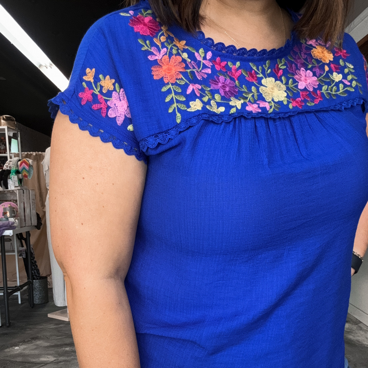 royal blue top with bright colored embroidered flowers on the front top and sleeves