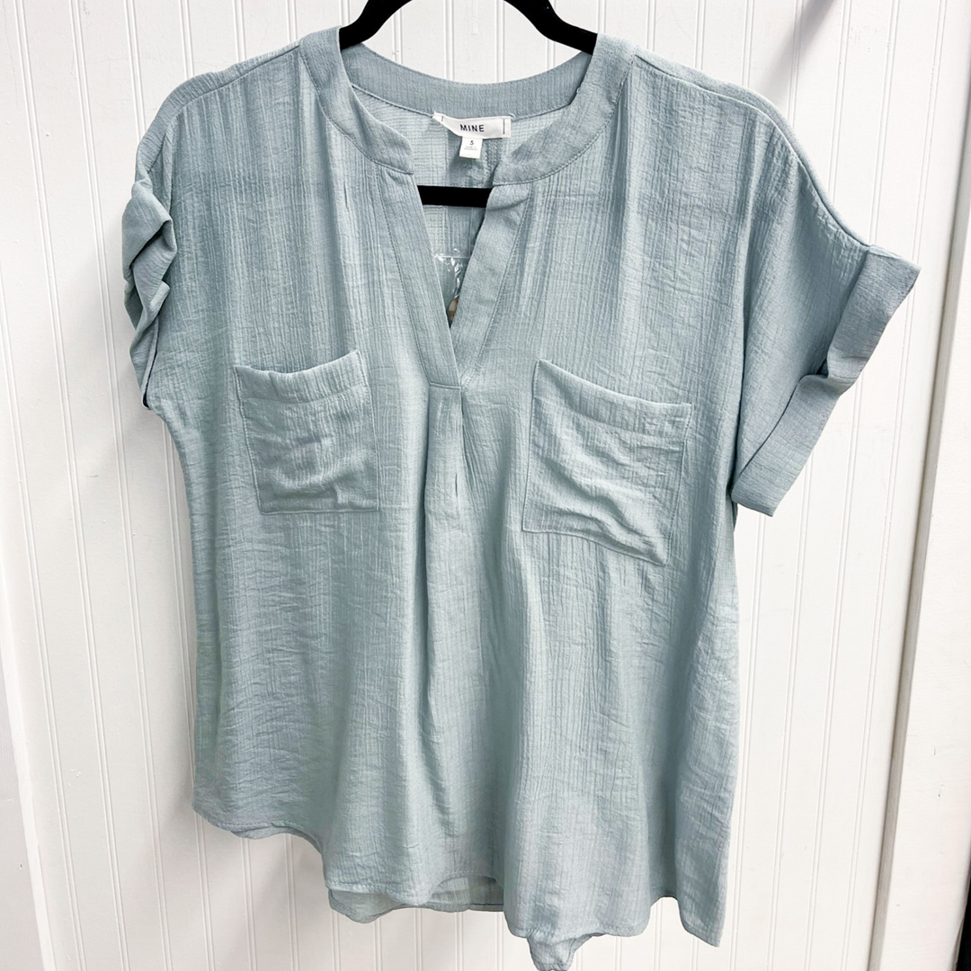 Easy To Style Sage Woven Top, woven women's short sleeve top with v-neck with detail. double front pocket detail. back button detail going down the center. 