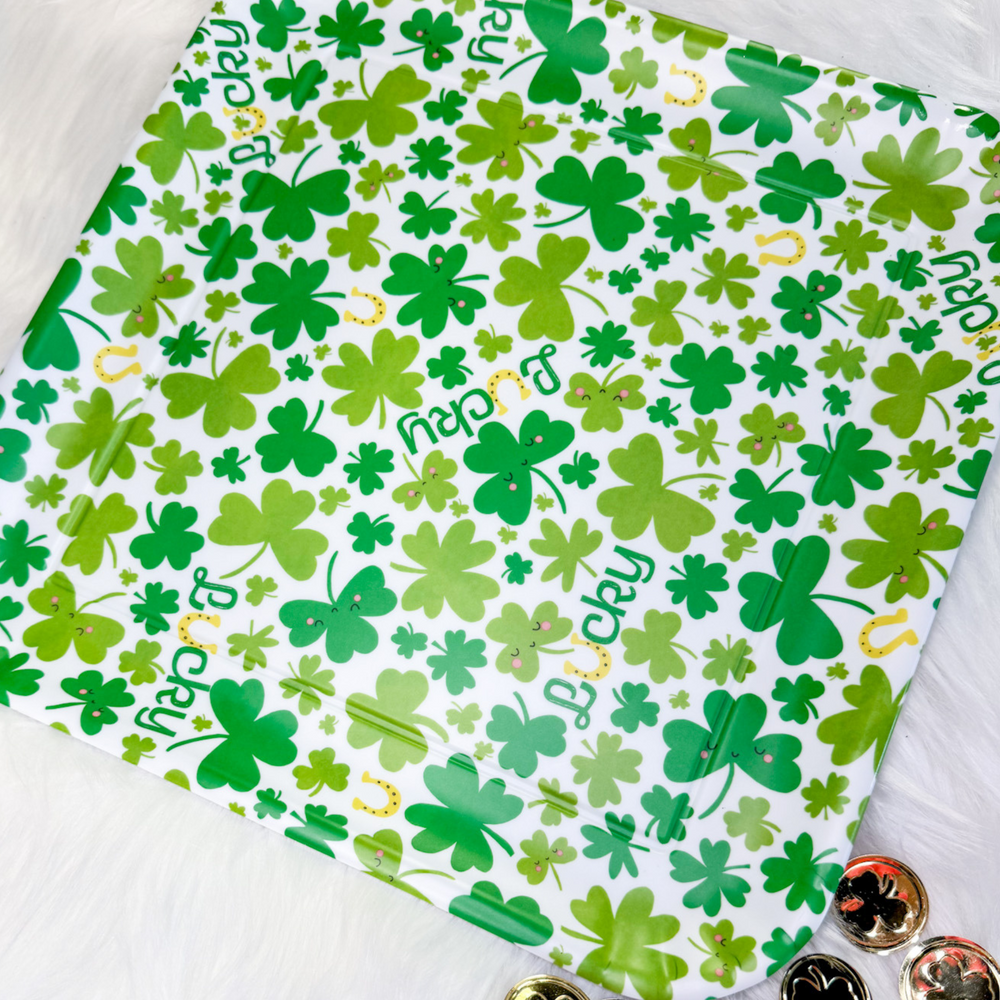 St. Patrick's Day melamine platter, 4 leaf clovers in different shades of green on a white background, gold horseshoes, the word lucky in green cursive with the "u" as a gold horseshoe. 