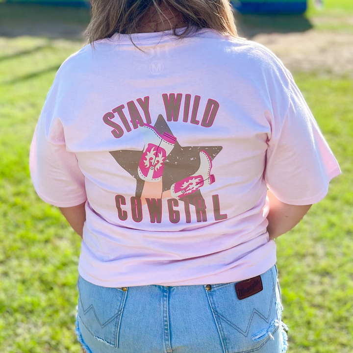 pink graphic tee that says stay wild cowgirl on the back in brown, pink with a brown star and cowgirl boots. 