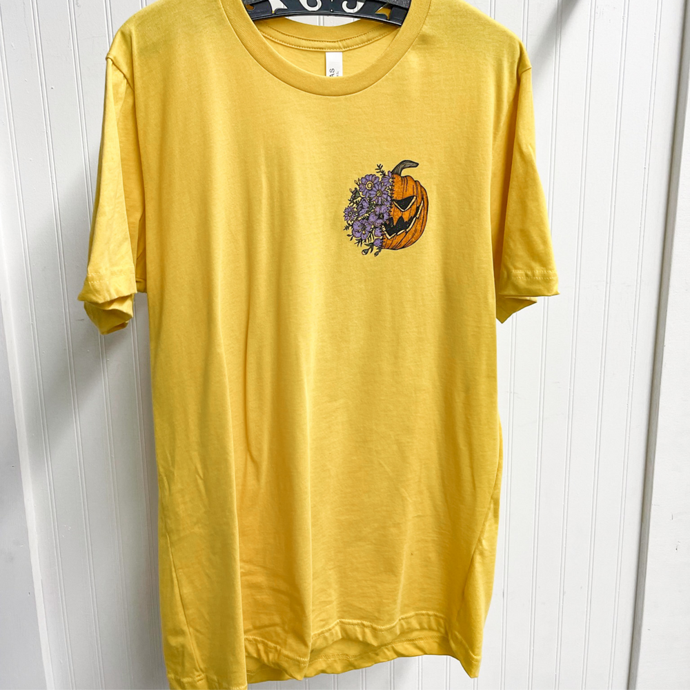 halloween graphic tee shirt, yellow shirt with a graphic on the chest, half a jack o lantern face and the other half a bundle of purple flowers. The back with a big image of the same. 