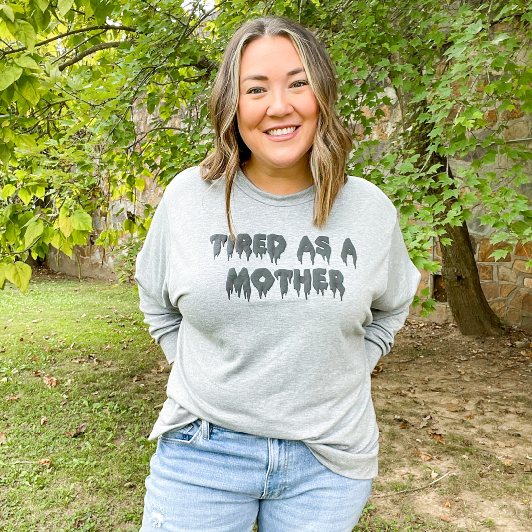 tired as a mother tee, long sleeve soft grey halloween graphic tee, tired as a mother in a melting font. the letter color is a darker grey with a puffy texture. 