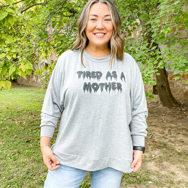 tired as a mother tee, long sleeve soft grey halloween graphic tee, tired as a mother in a melting font. the letter color is a darker grey with a puffy texture. 