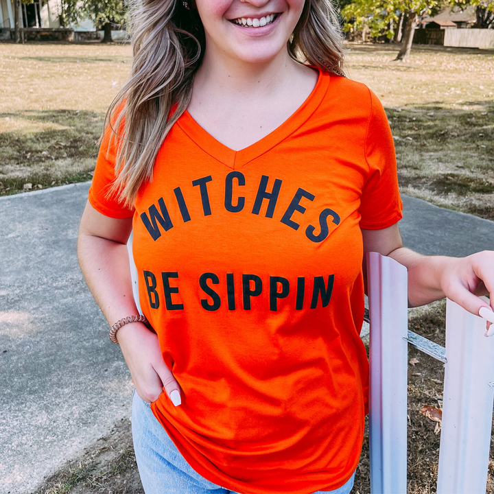 witches be sippin graphic tee, super soft orange womens tee shirt with the words witches be sippin on the front. v-neck with round hem at the bottom. 