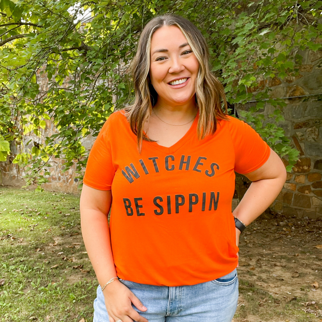 witches be sippin graphic tee, super soft orange womens tee shirt with the words witches be sippin on the front. v-neck with round hem at the bottom. 